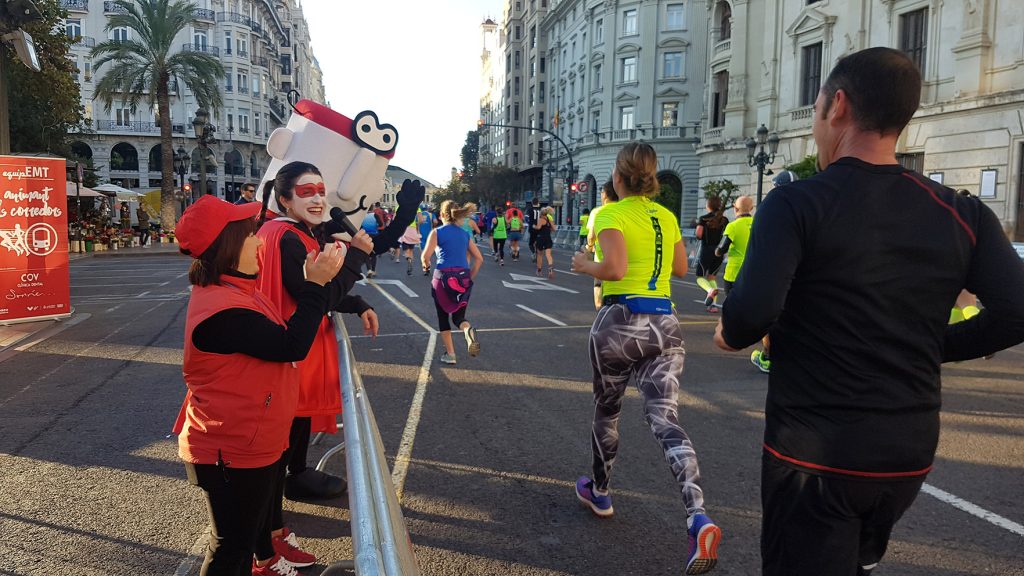 Imagen de corredores en la maratón de Valencia con mujeres animando a su paso