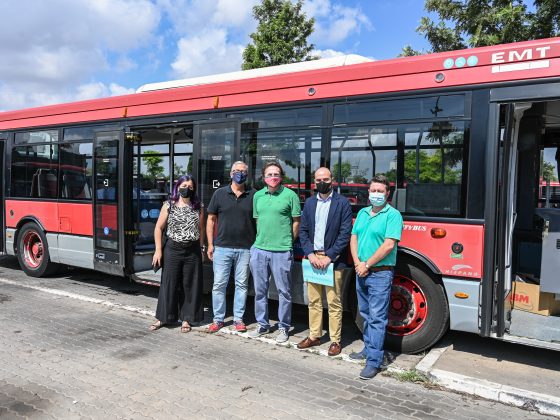 Imagen de un autobús donado con los responsables de la operación